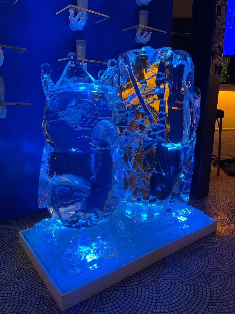 Escultura de gelo de um gato com coroa, iluminada a azul